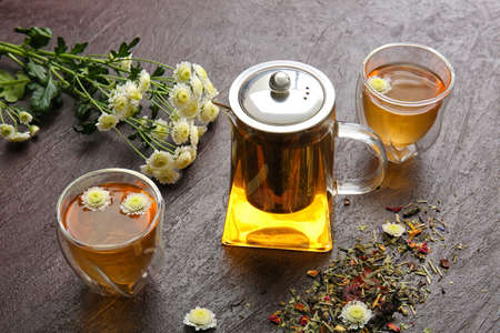Composition with teapot, glasses and flowers on color backgroundの写真素材