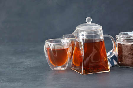Teapot with hot tea and glasses on dark backgroundの写真素材