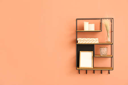 Modern shelf with books and decor on color wallの写真素材