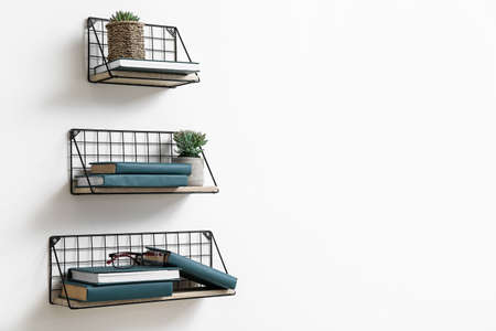 Modern shelves with books hanging on light wallの写真素材