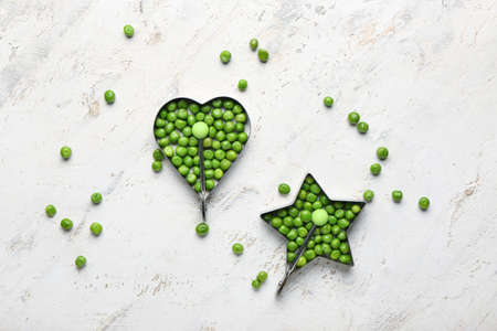 Cookie cutters with fresh green peas on light background