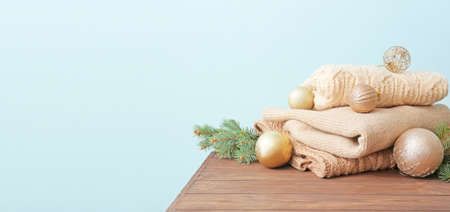 Christmas decorations with stylish winter clothes on table against color background with space for textの写真素材