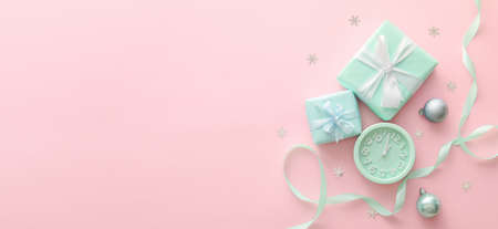 Alarm clock with gifts and Christmas decorations on pink background with space for textの写真素材
