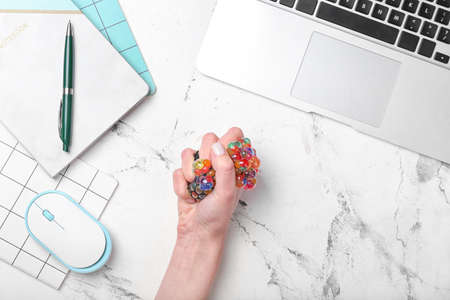 Female hand squeezing stress ball on light backgroundの写真素材