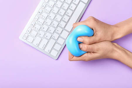 Female hands squeezing stress ball while working on color backgroundの写真素材