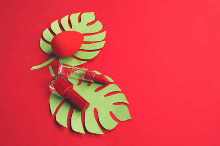 Makeup supplies with tropical leaves on color backgroundの写真素材