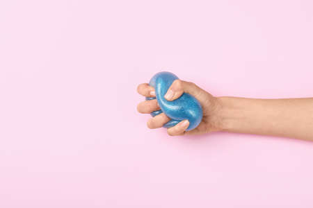 Female hand squeezing stress ball on color background