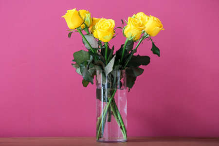 Vase with beautiful yellow roses on color backgroundの写真素材