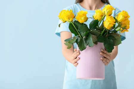 Woman with bouquet of beautiful yellow roses on color backgroundの写真素材