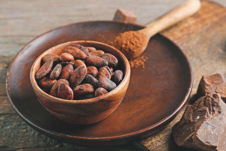 Bowl with cocoa beans on wooden backgroundの写真素材