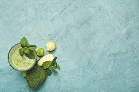 Glass of healthy green smoothie and ingredients on color backgroundの写真素材