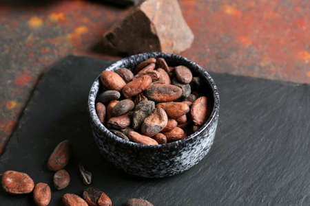 Bowl with cocoa beans on grunge backgroundの写真素材