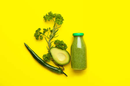 Bottle of healthy green smoothie and ingredients on color backgroundの写真素材