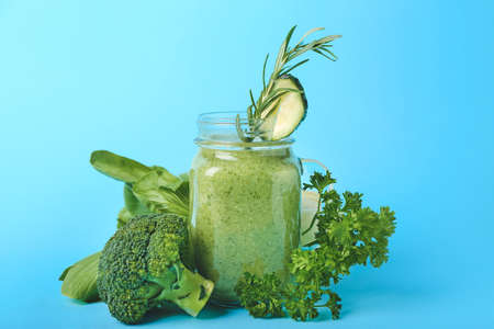 Mason jar of healthy green smoothie and ingredients on color backgroundの写真素材