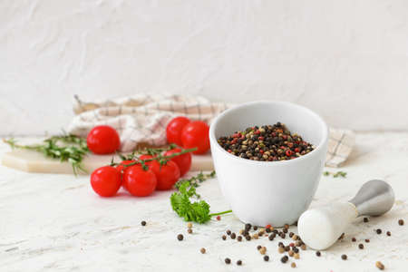 Mortar and pestle with peppercorns on light backgroundの写真素材