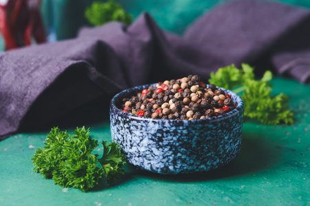 Bowl with peppercorns on color backgroundの写真素材