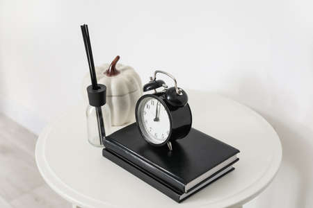 Table with books, alarm clock and decor near white wallの写真素材