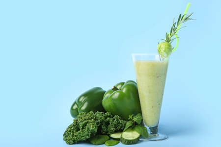 Glass of healthy green smoothie and ingredients on color backgroundの写真素材