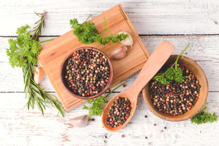 Bowls and spoon with peppercorns on light wooden backgroundの写真素材