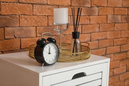 Alarm clock and decor on table near brick wallの写真素材