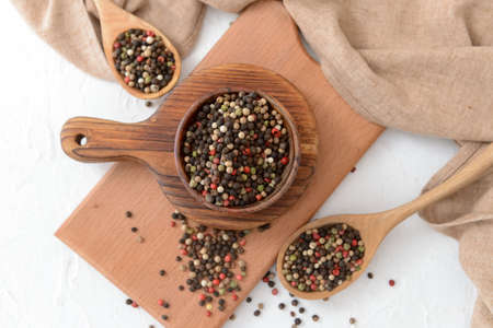 Bowl and spoons with peppercorns on light backgroundの写真素材