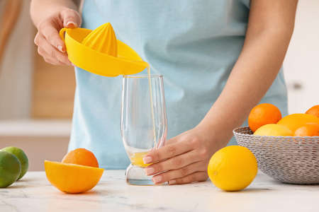 Woman making orange juice on light table in kitchenの写真素材