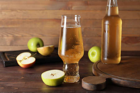 Bottle and glass with apple cider on wooden backgroundの写真素材