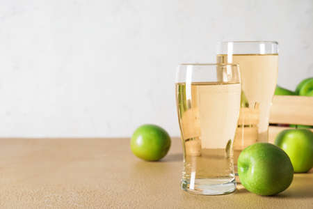 Glasses of cold apple cider and box on tableの写真素材