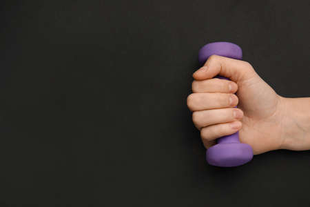 Female hand with dumbbell on dark backgroundの写真素材