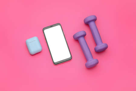 Dumbbells, mobile phone and earphones on pink backgroundの写真素材