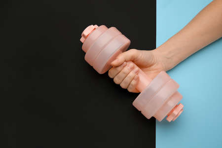 Female hand with dumbbell on dark background