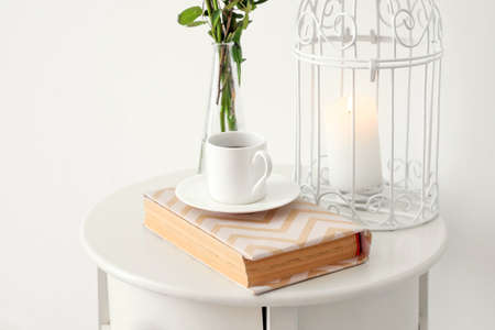 Bedside table with cup of coffee and book near white wallの写真素材