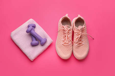 Dumbbells, towel and shoes on pink backgroundの写真素材
