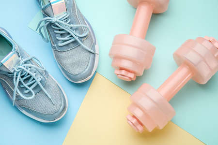 Dumbbells and shoes on color backgroundの写真素材