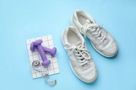 Dumbbells, shoes and measuring tape on blue backgroundの写真素材
