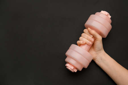 Female hand with dumbbell on dark backgroundの写真素材