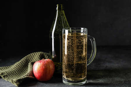 Bottle and mug of apple cider on dark backgroundの写真素材