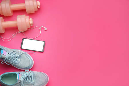 Dumbbells, mobile phone and shoes on pink backgroundの写真素材