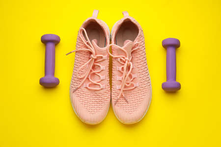 Dumbbells and shoes on yellow backgroundの写真素材