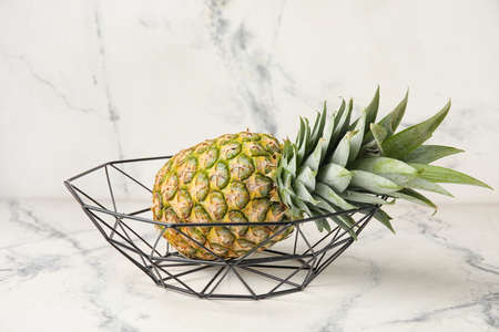 Basket with fresh pineapple on white background