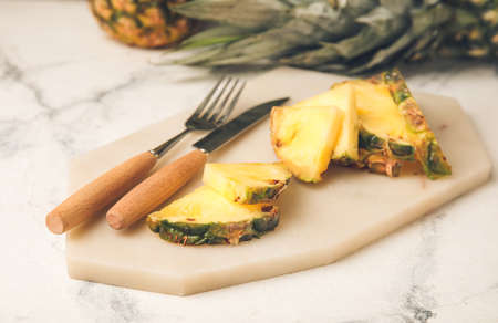Board with slices of fresh pineapple on table