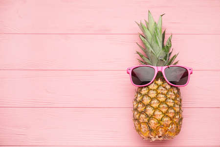 Pineapple with sunglasses on color wooden backgroundの写真素材