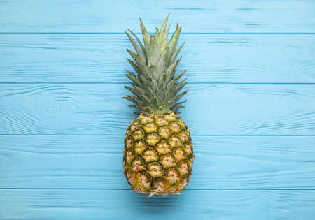 Fresh pineapple on color wooden background