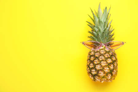 Pineapple with sunglasses on color background