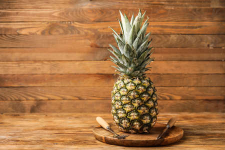 Plate with fresh pineapple and cutlery on wooden backgroundの写真素材