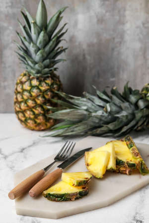 Board with slices of fresh pineapple on tableの写真素材