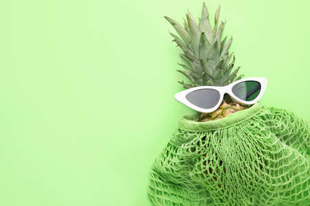 Pineapple with sunglasses and shopping bag on color backgroundの写真素材