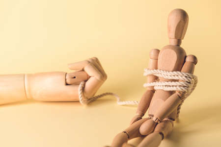Hand and mannequin with tied around rope on color background. Concept of hostageの写真素材