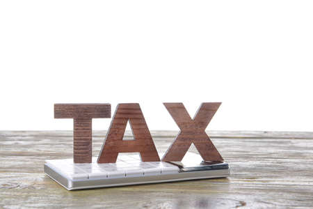 Word TAX with calculator on table against white backgroundの写真素材