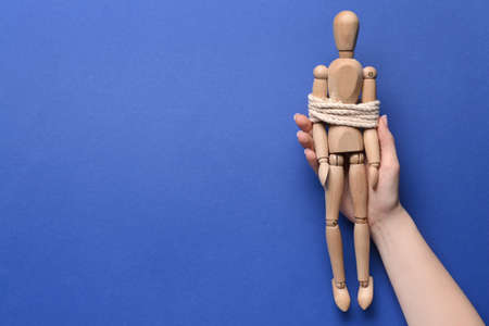 Hand and mannequin with tied around rope on color background. Concept of hostageの写真素材